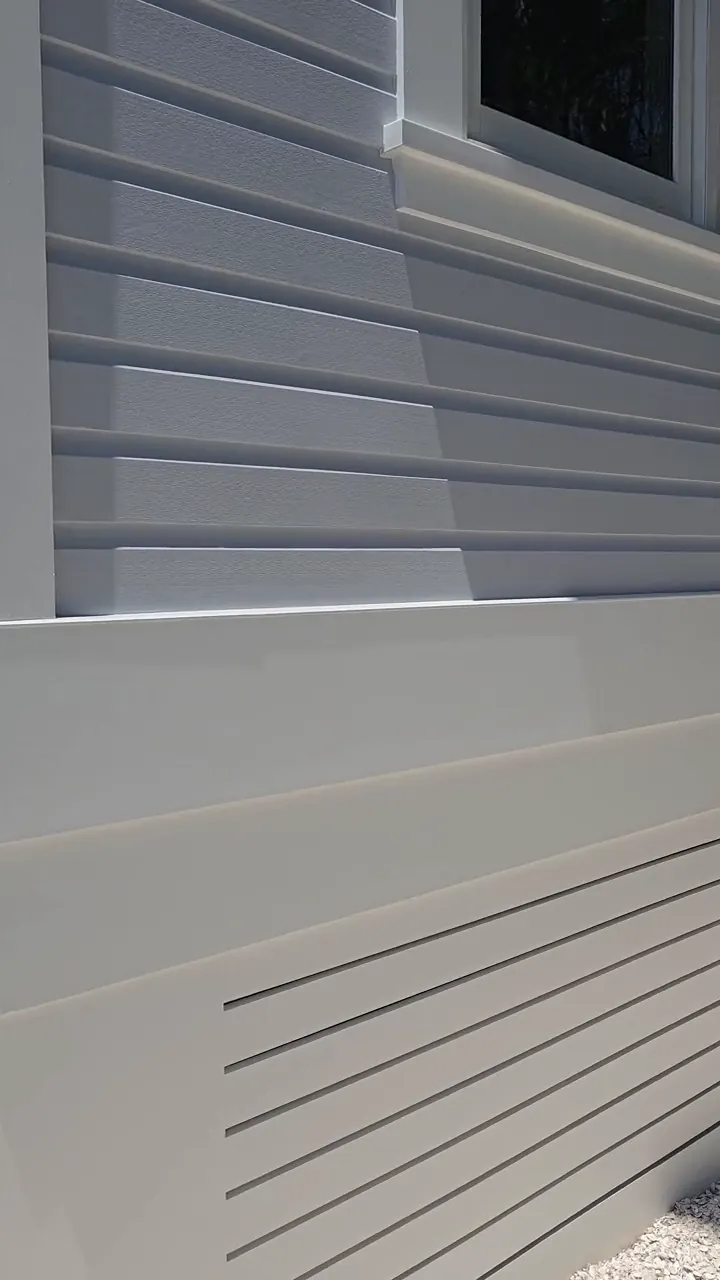 Lap siding and a louvred skirt vent coated in the same tone, the slats cut in by hand so the shadow lines stay crisp.