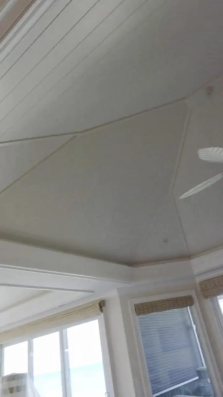 Layered tray ceiling with crown molding finished in white above a dining room, furniture still under cover.