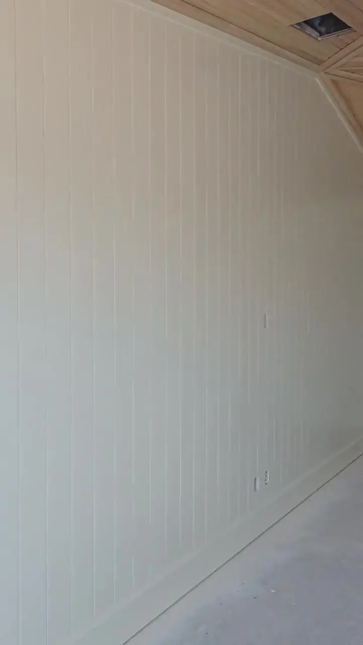 Room beneath a vaulted stained plank ceiling with painted walls and trim taken to a clean edge.