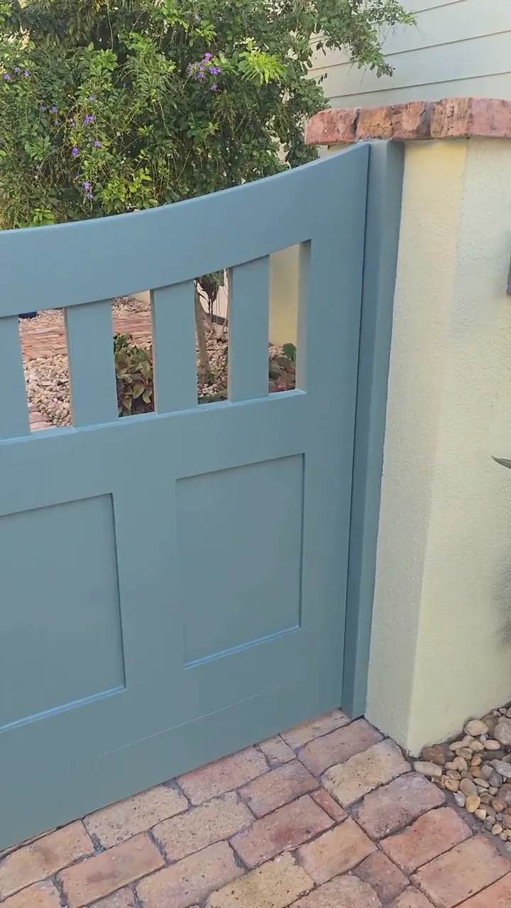 The rebuilt gate hung and finished in teal, strap hinges and thumb latch back in place over a brick paver drive.